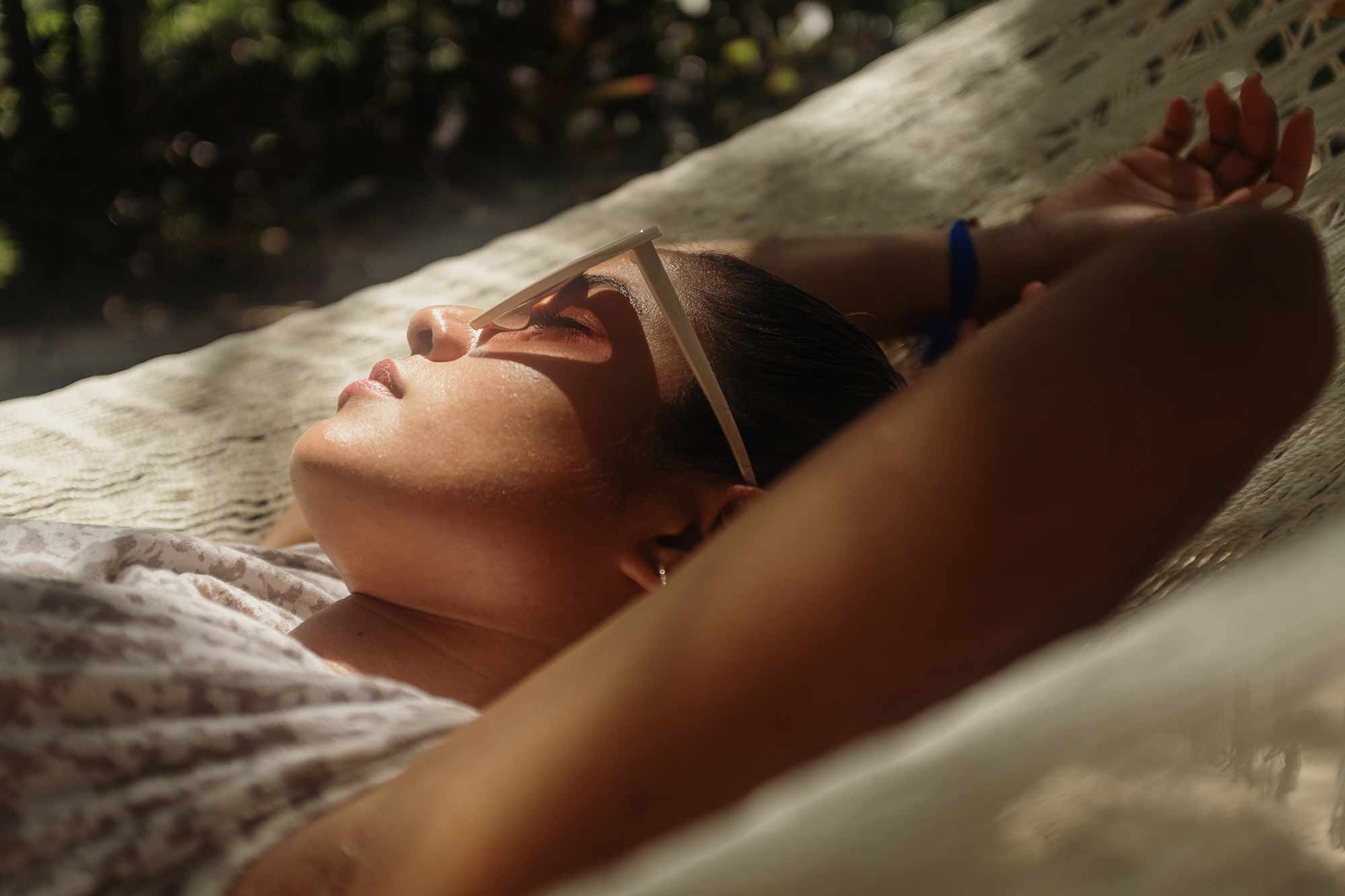 Woman relaxing peacefully in the sunlight with eyes closed, surrounded by soft shadows